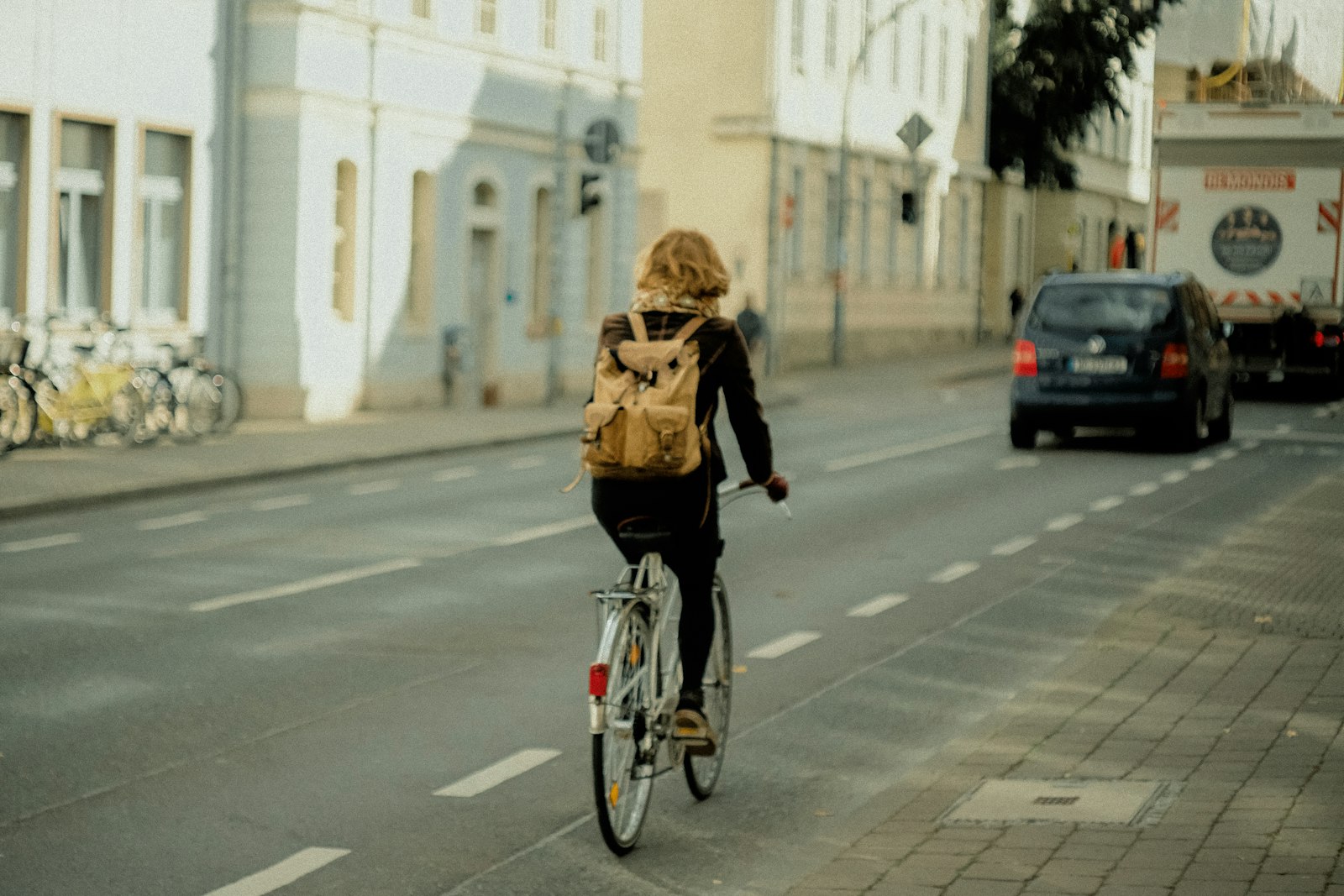 Cyklist med ryggsäck pendlar på en cykelbana i staden