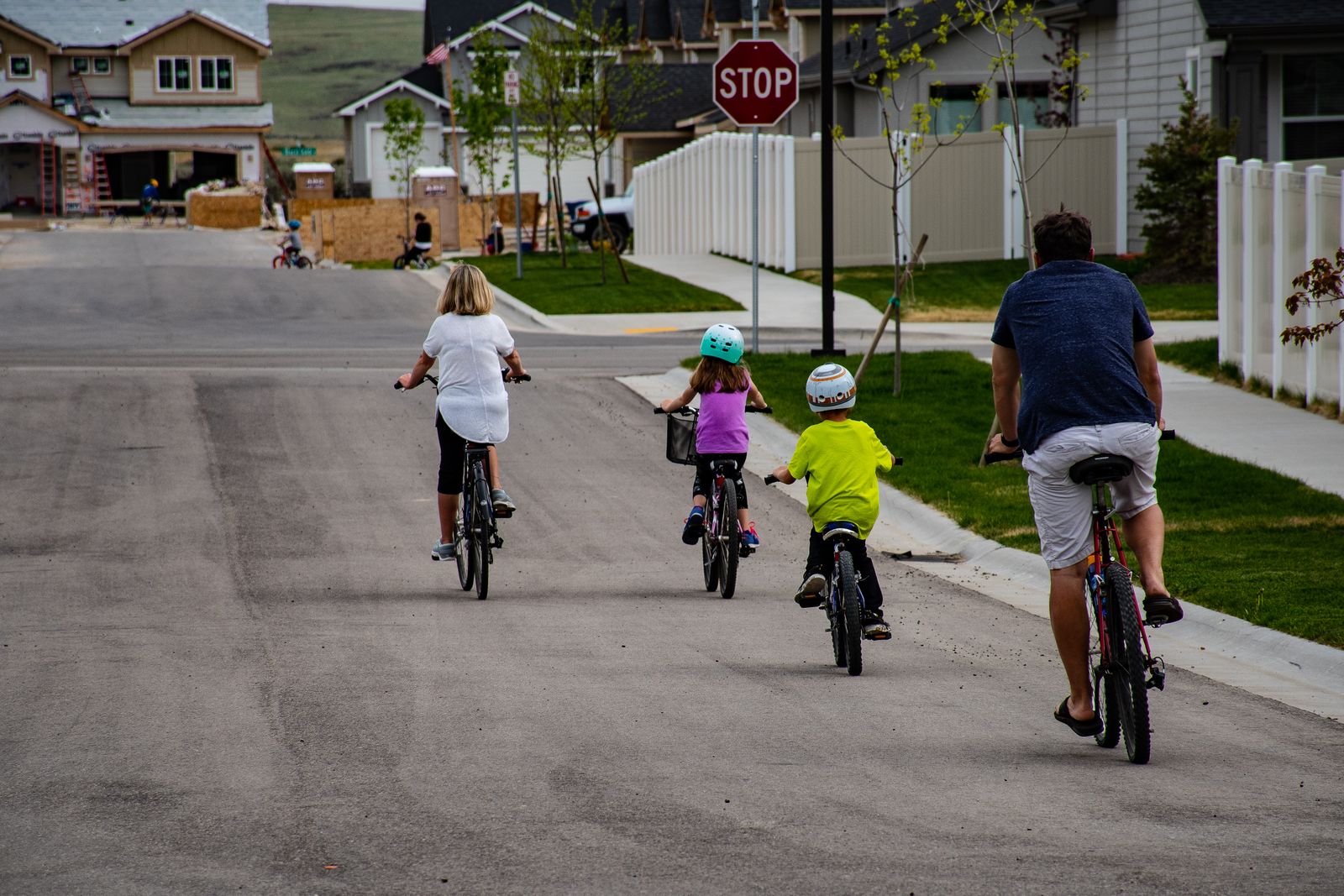Familj cyklar tillsammans, barn pa cyklar i olika storlekar