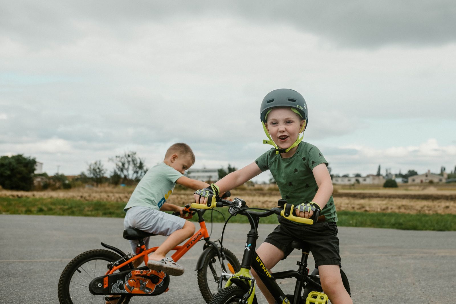 Tva barn med hjalm pa cyklar pa en vag