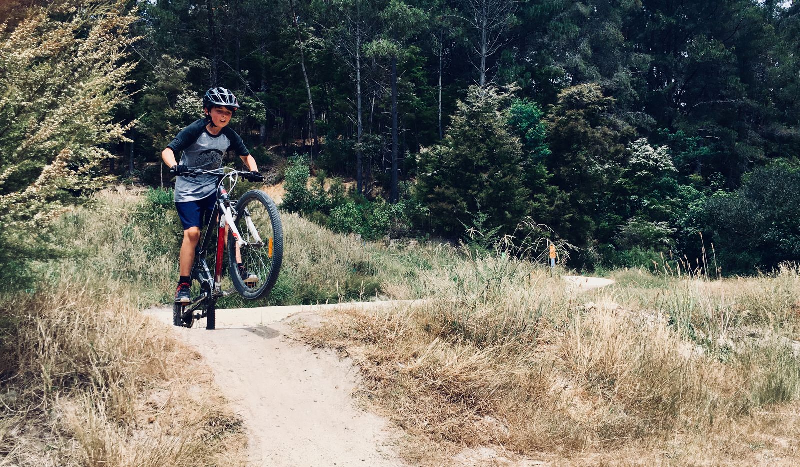 Ungdom med hjalm pa mountainbike pa en stig