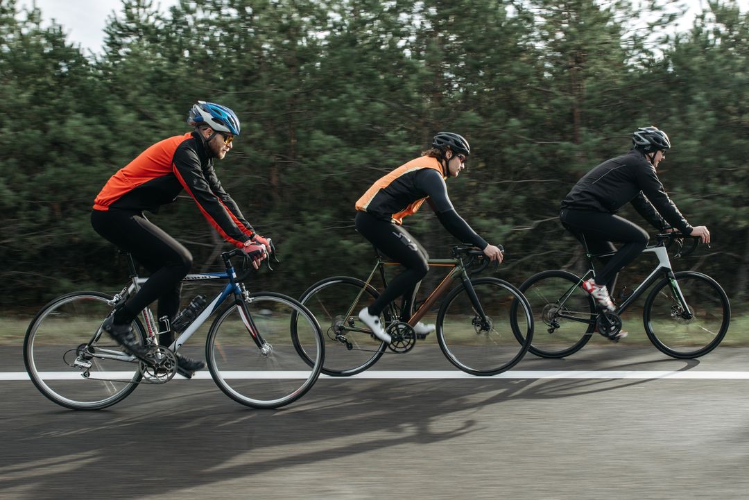 Tre cyklister på landsvägscyklar sedda från sidan