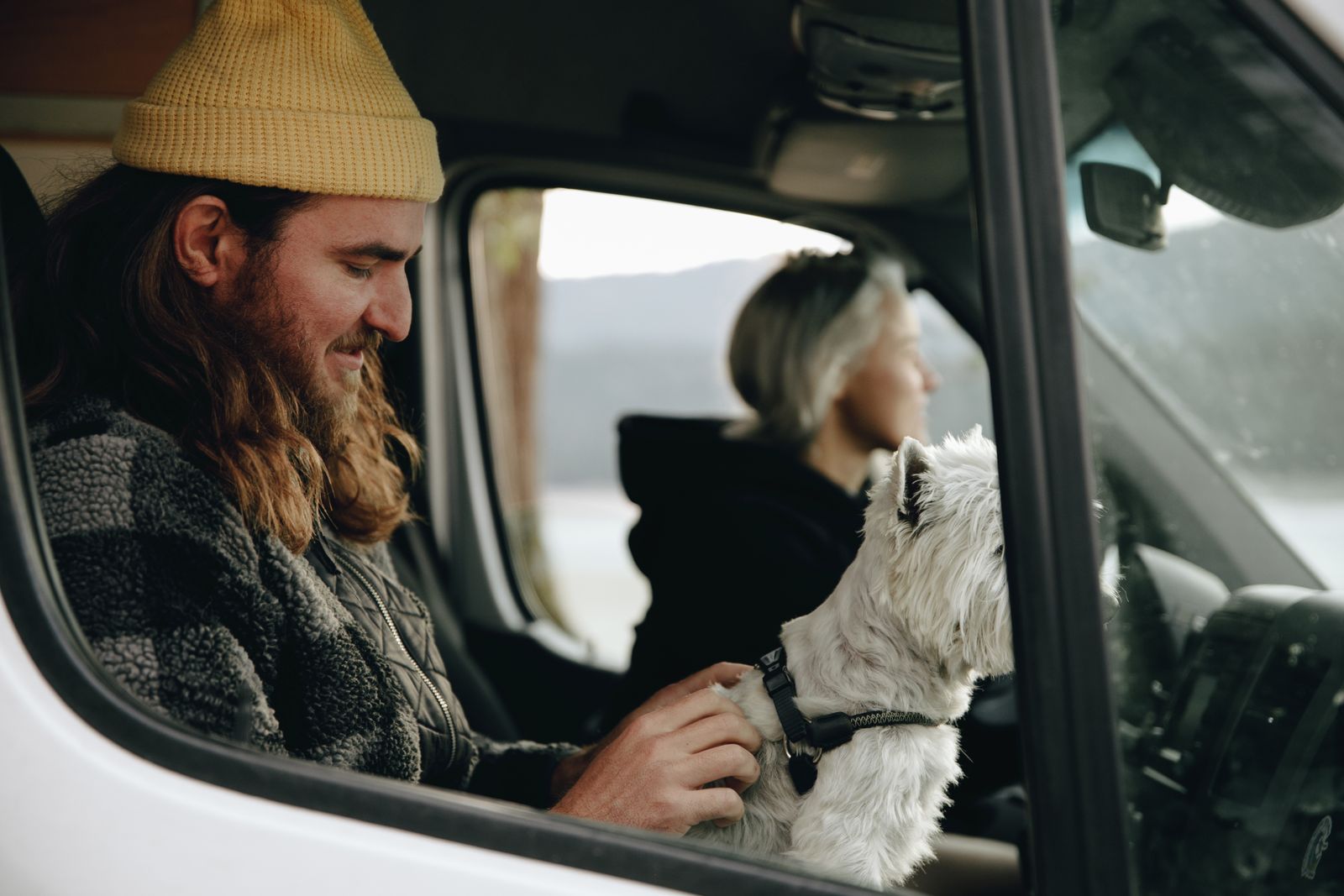 Par sitter i en husbil tillsammans med sin vita terrier