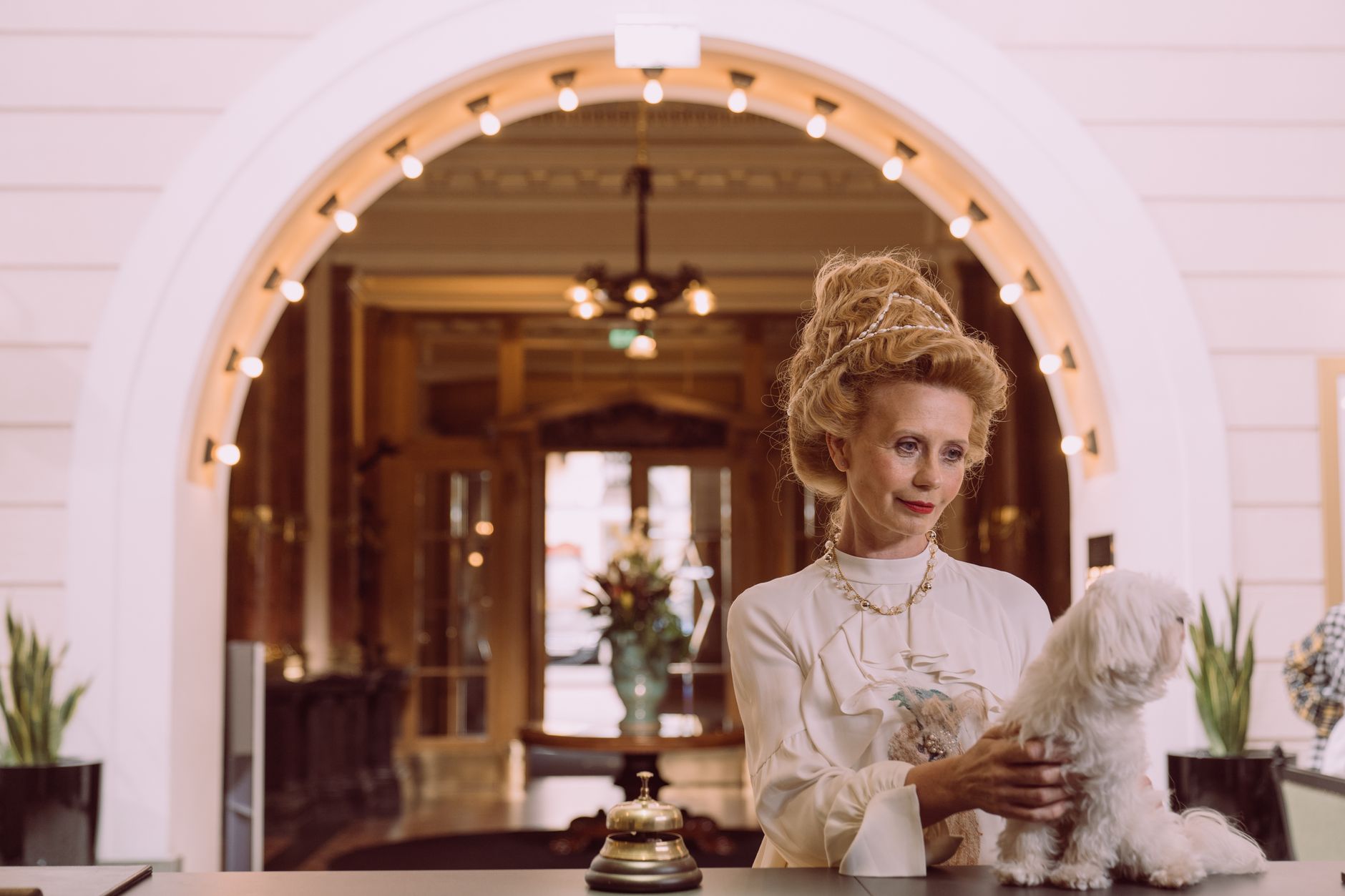 Kvinna med en liten vit hund på disken i en hotellreception