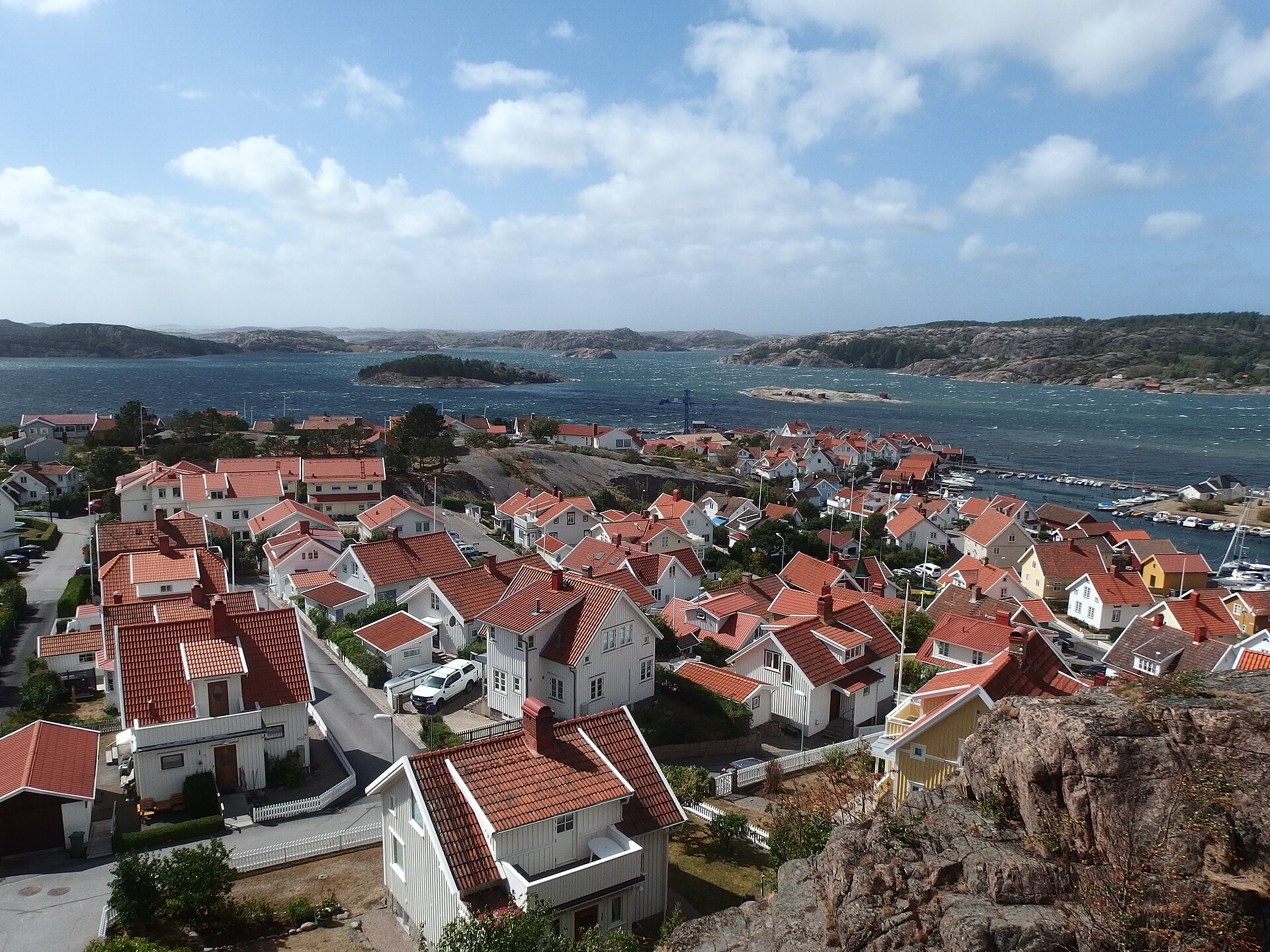 Fjällbackas vita trähus med röda tak och havet med skärgården bakom
