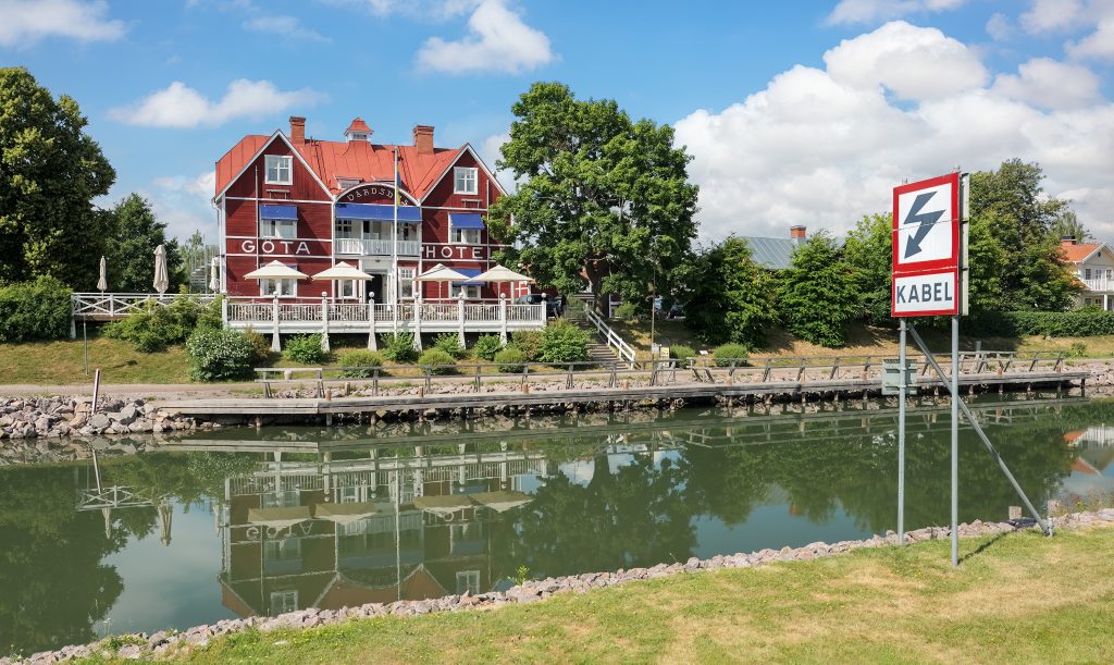 Göta Hotell i Borensberg speglar sig i Göta kanal en sommardag