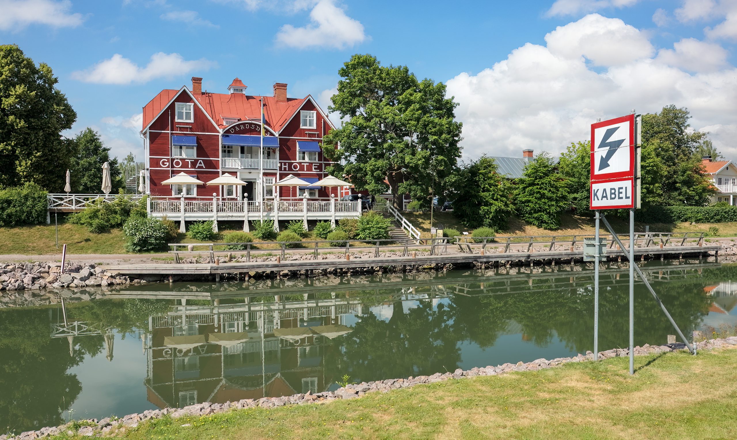 Göta Hotell i Borensberg speglar sig i Göta kanal en sommardag