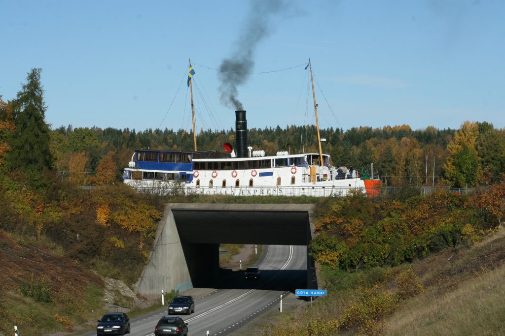 Ångbåten Motala Express på Göta kanal ovanför riksväg 34 vid Kungs Norrby, där vägen går ner i en betongtunnel