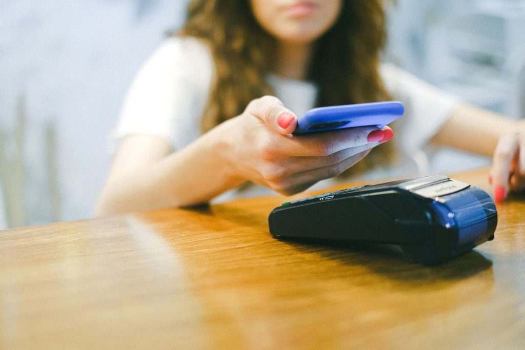 Person betalar kontaktlöst med mobiltelefon mot en kortterminal