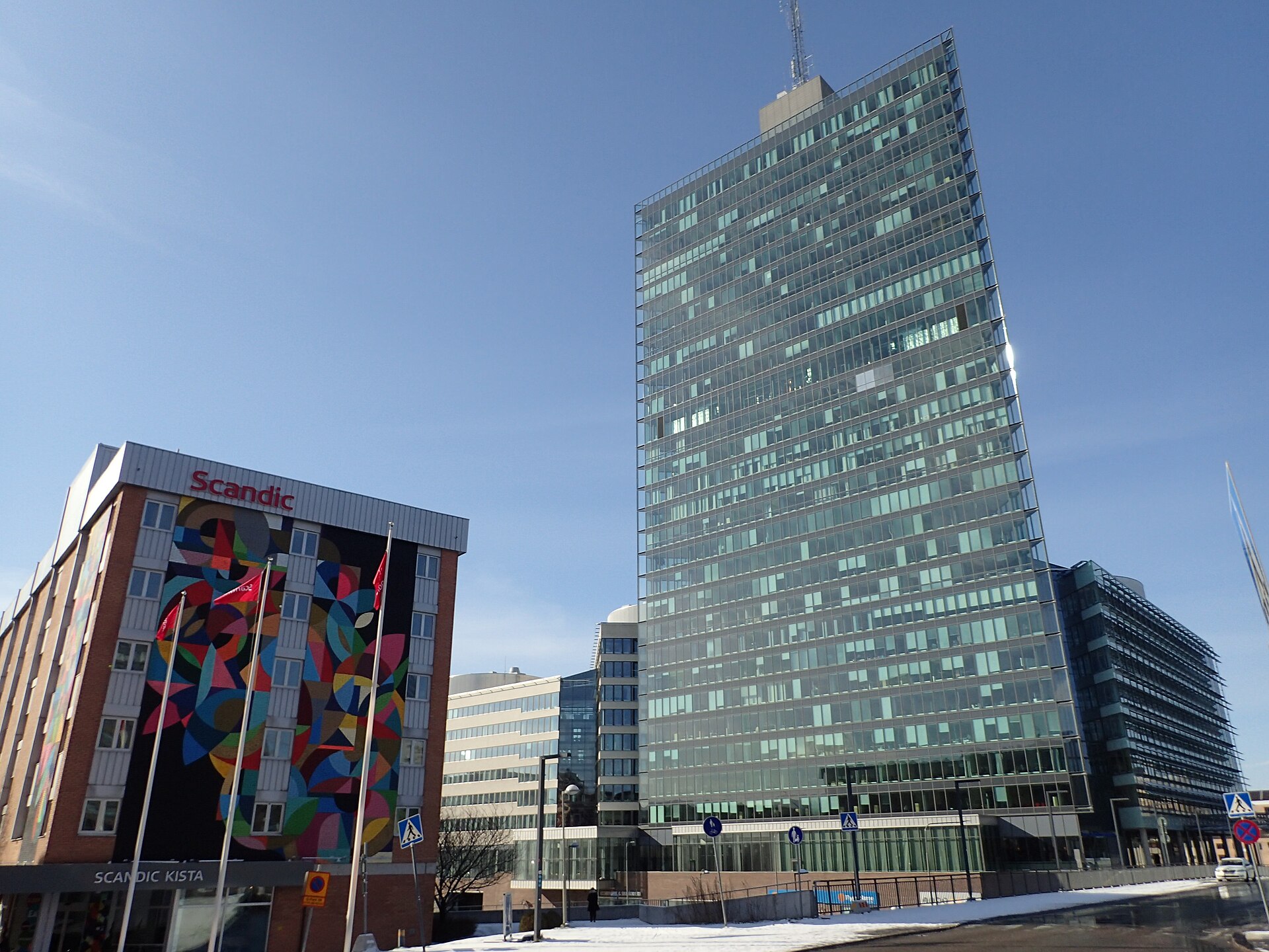 Kista Science Tower i glas reser sig bakom lägre kontors- och hotellbyggnader i Kista i Stockholm