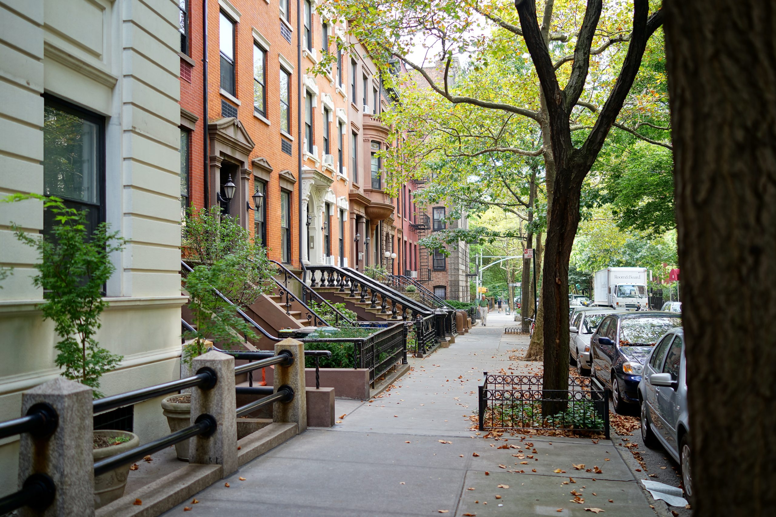 Radhus med trappor och träd längs en gata i Brooklyn Heights
