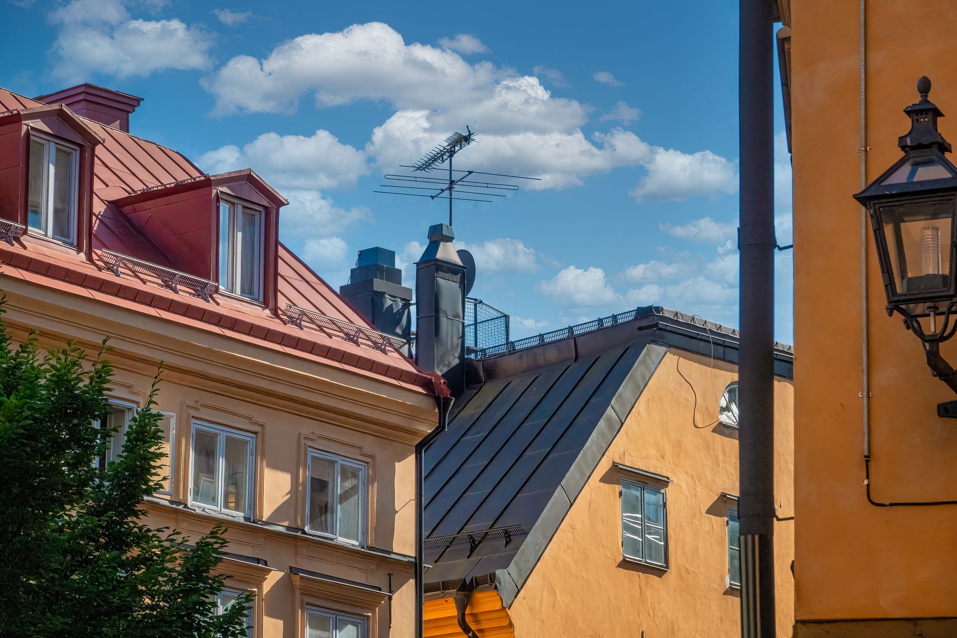 Takåsar med plåttak och skorstenar i centrala Stockholm mot blå himmel