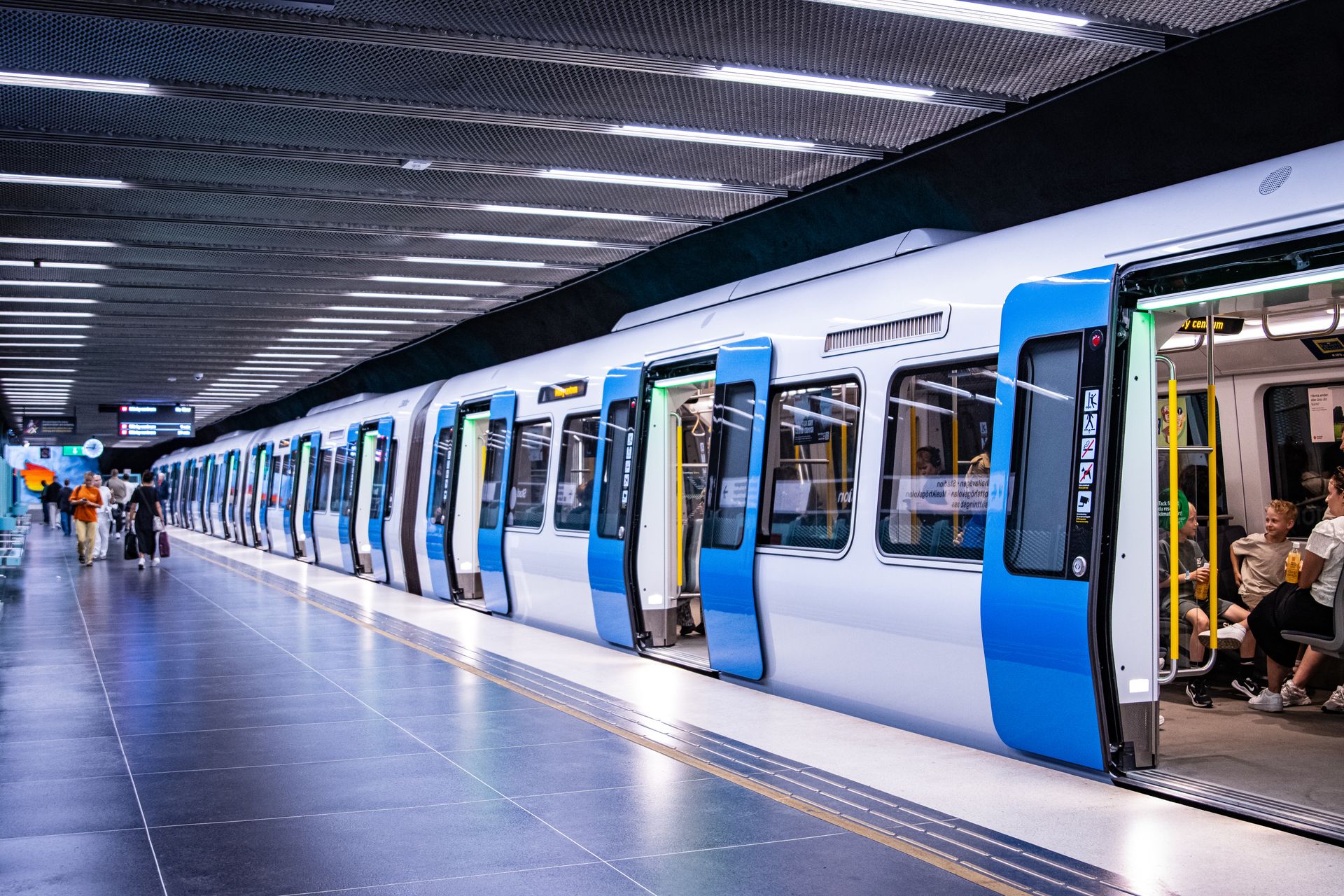 Blåvitt tunnelbanetåg med öppna dörrar vid en plattform i Stockholms tunnelbana