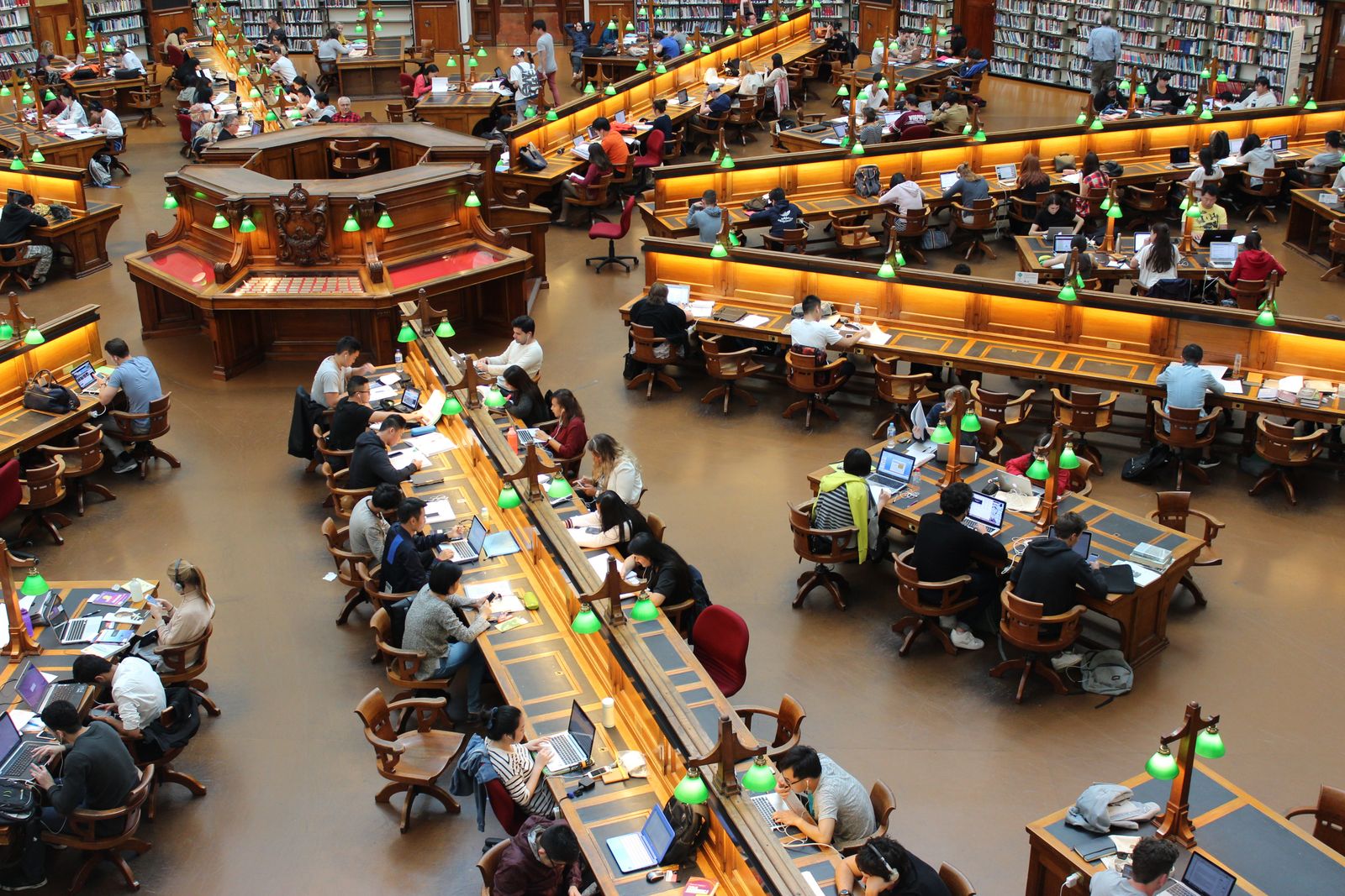 Studenter som pluggar vid långbord i ett universitetsbibliotek