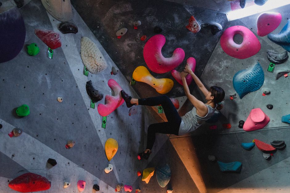 Person som klättrar på en färgglad boulderingvägg inomhus