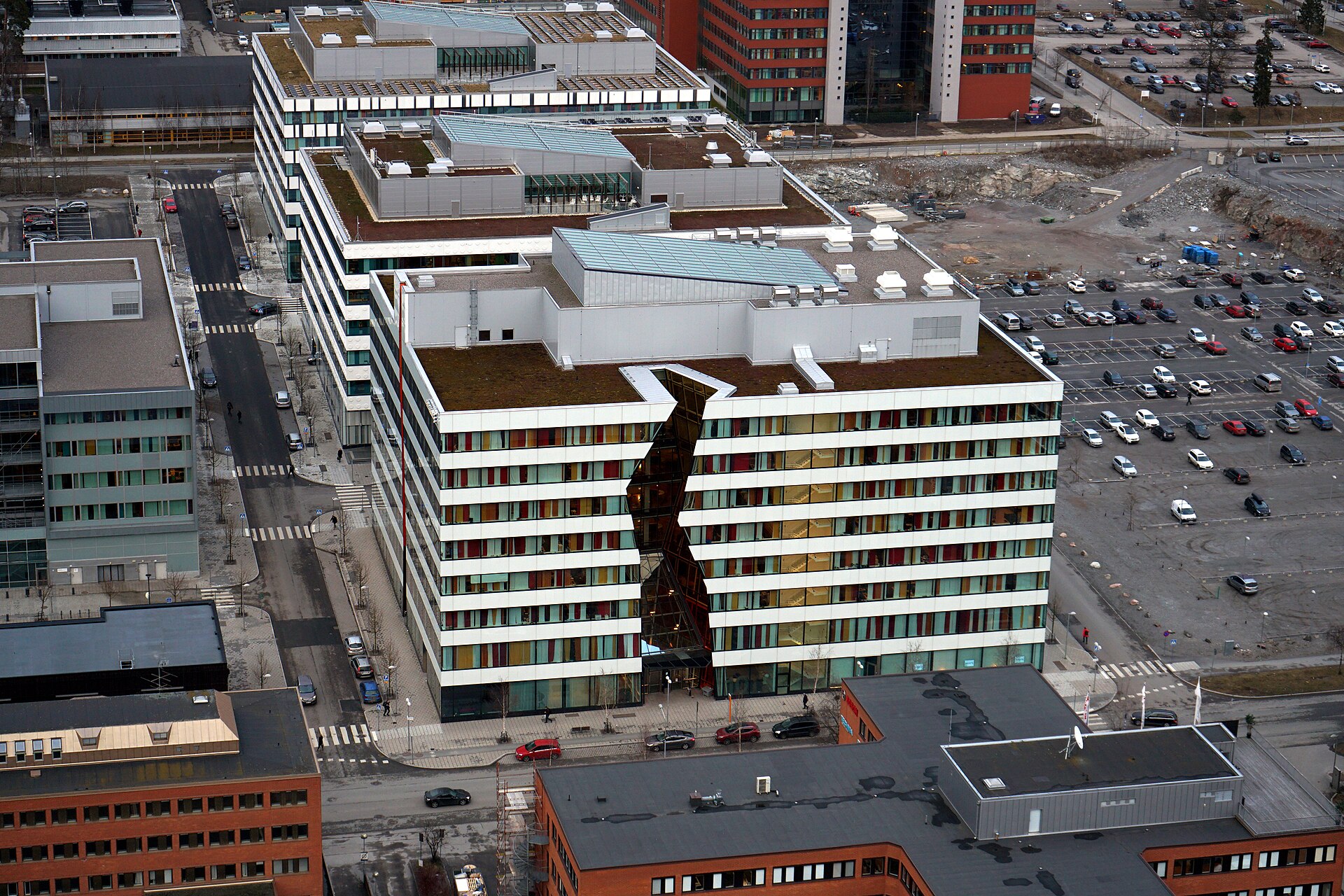 Ericssons vita kontorshus i Kista sett uppifrån från Kista Science Tower, med parkering och tegelkontor runt omkring