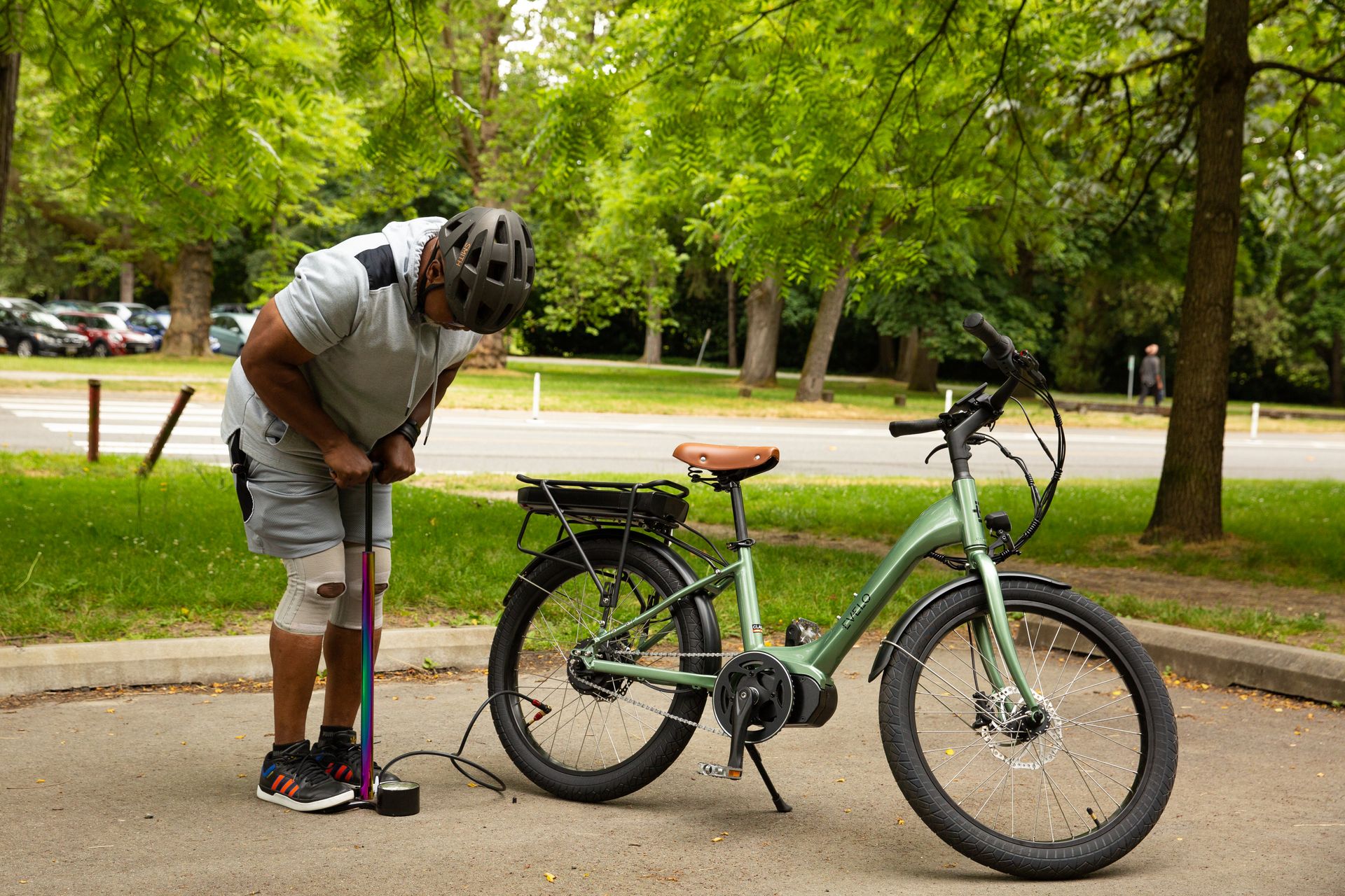 Man kontrollerar däcktrycket på en grön elcykel i en park