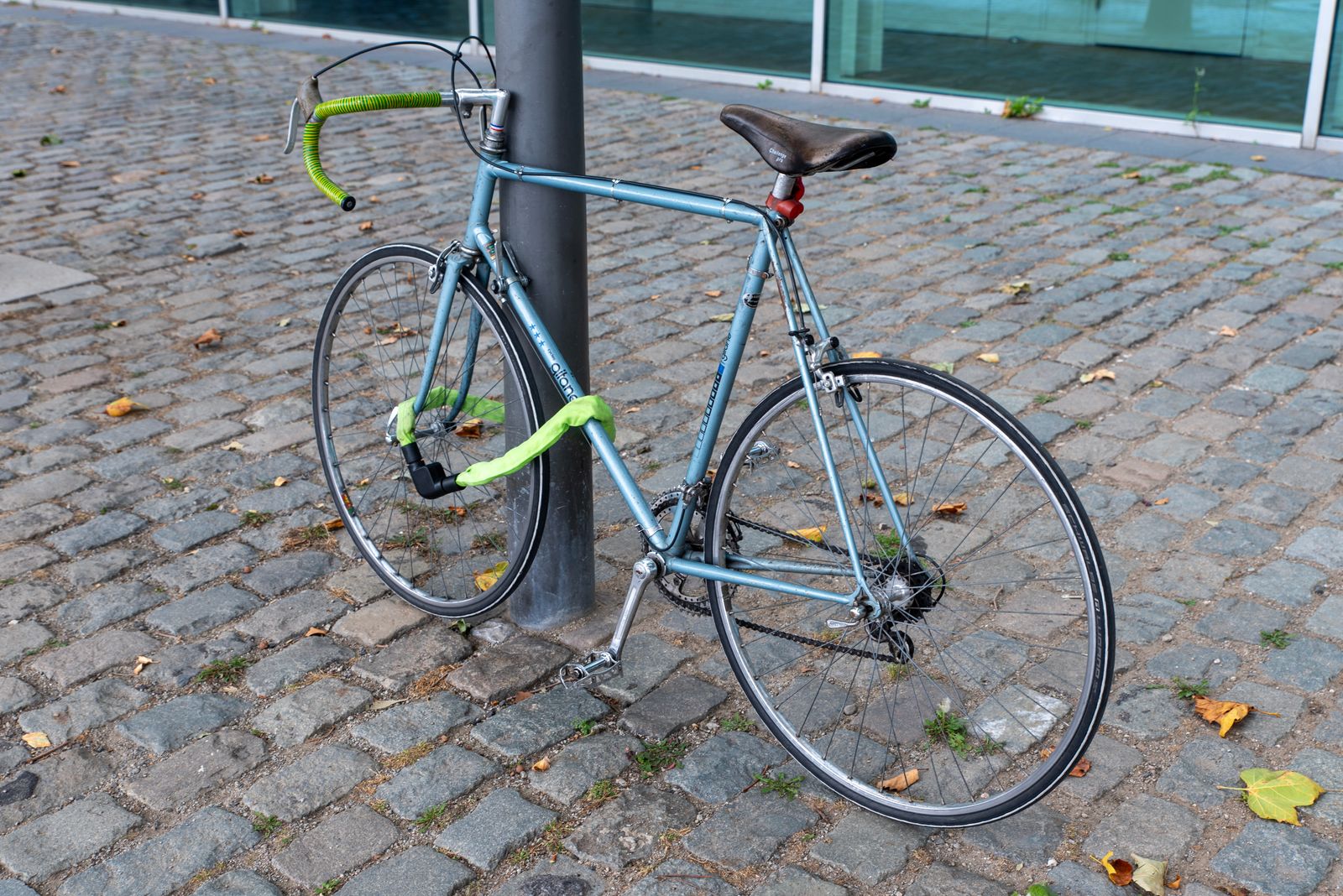 Cykel fastlåst vid en stolpe med ett lås genom ramen