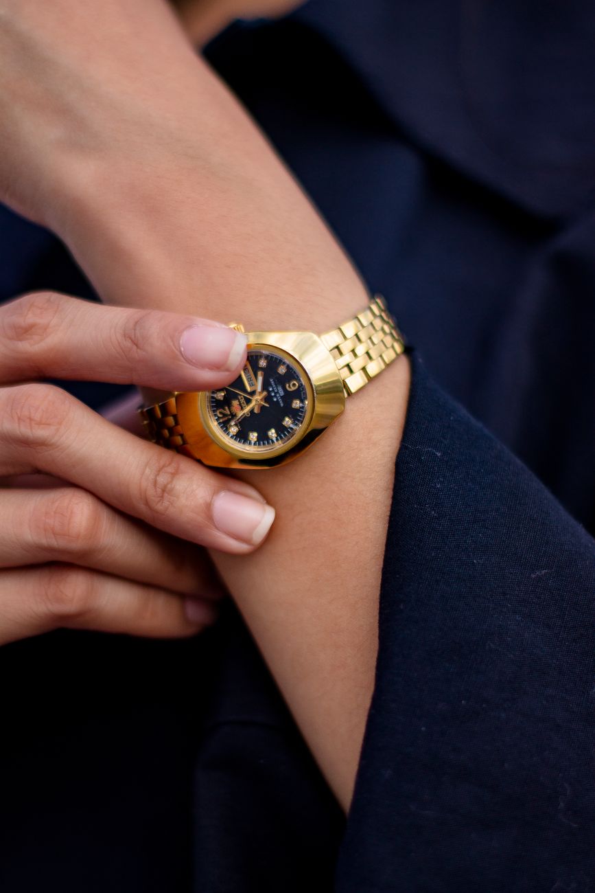Guldfärgat armbandsur med svart urtavla på en handled