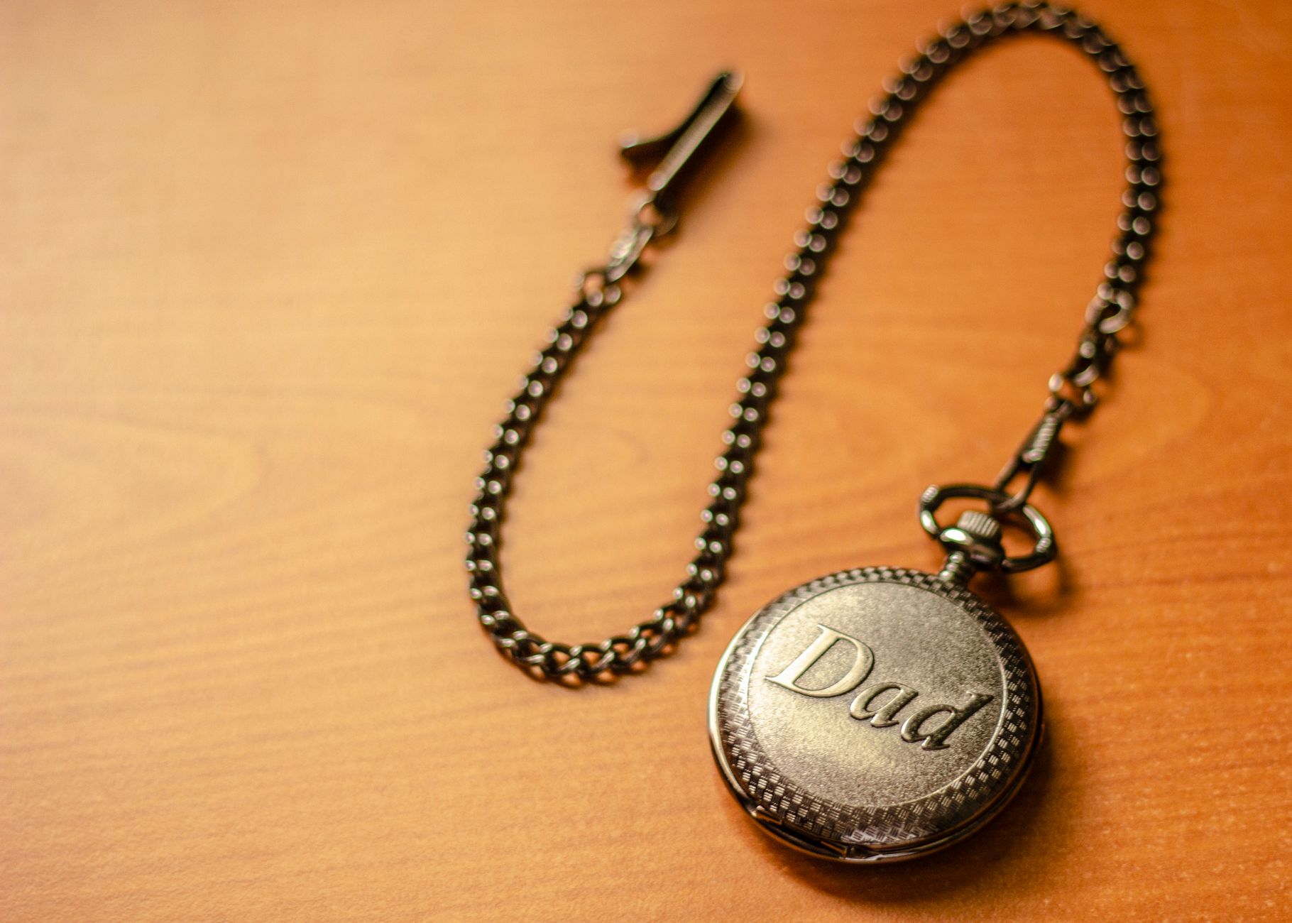 Fickur med ordet Dad på locket och en lång kedja på ett träbord