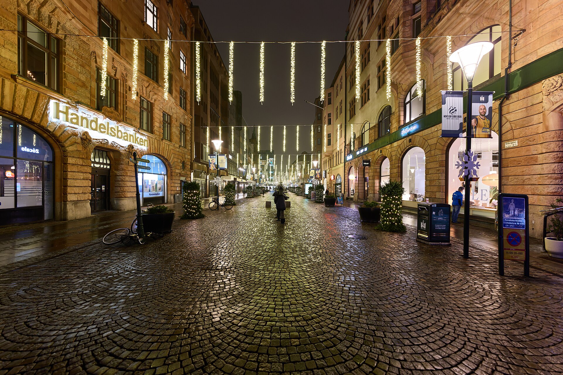Södergatan i Malmö en kväll med ljusslingor över gatan och upplysta butiksfönster längs kullerstenen