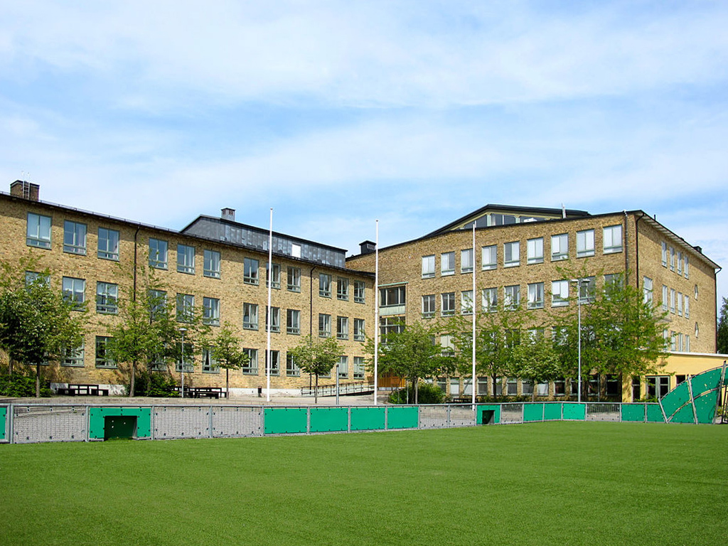 Skolbyggnad och grön fotbollsplan i Aspudden, Stockholm