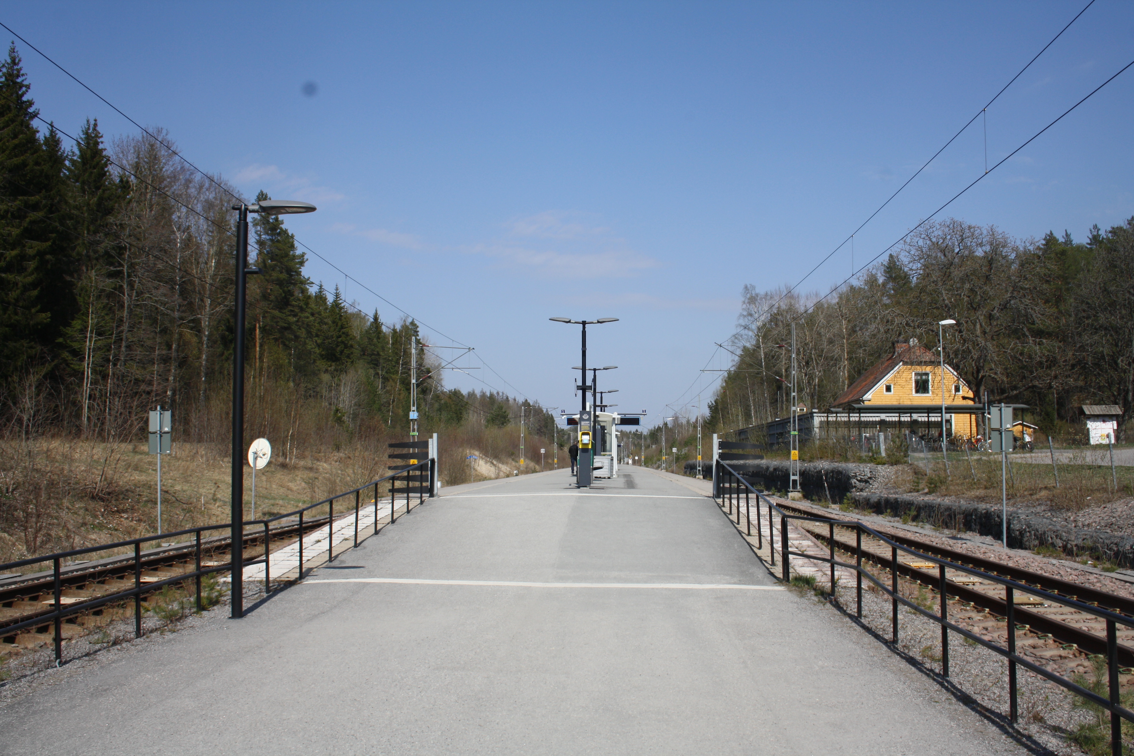 Segersängs pendeltågsstation med gult stationshus en solig vårdag
