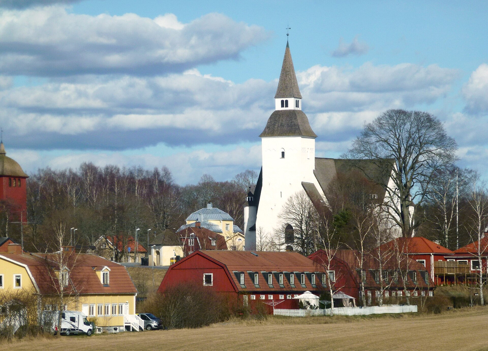 Sorunda kyrka, vit medeltidskyrka med högt torn, sedd över bygden