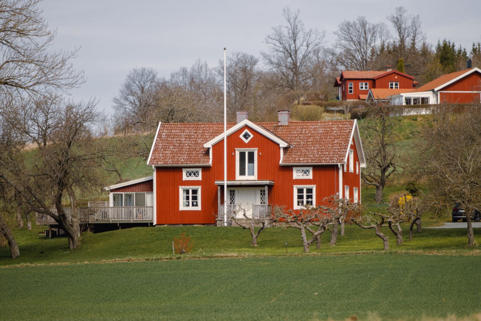 Röd svensk gårdsbyggnad i ett öppet landskap i Sorunda