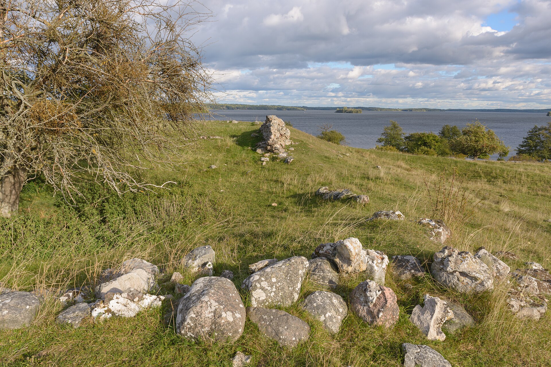 Ruinen efter Alsnö hus på en betad backe på Adelsö, med Mälaren och låga öar i bakgrunden
