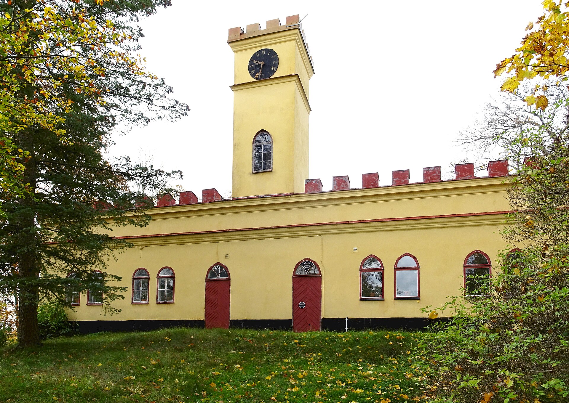 Citadellet vid Ekebyhovs slott, en gul byggnad med klocktorn, tinnar och spetsbågiga fönster