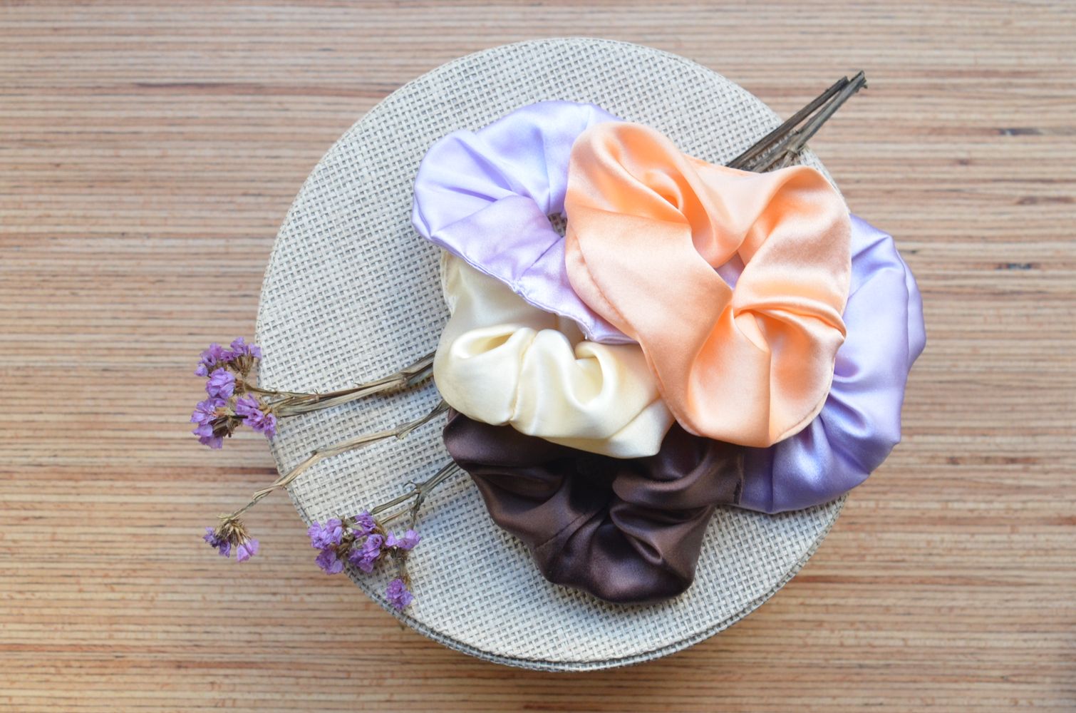 Flera sidenscrunchies i olika färger samlade på en rund ask