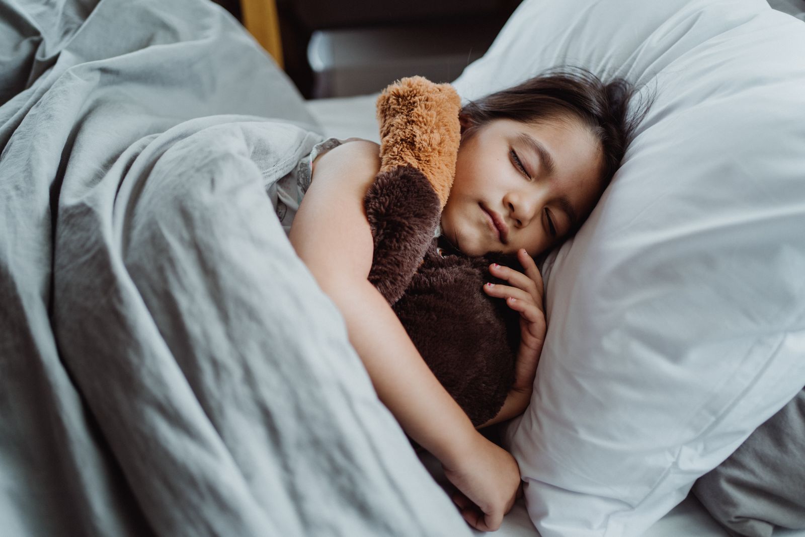 Ett barn sover lugnt i sin säng med ett gosedjur