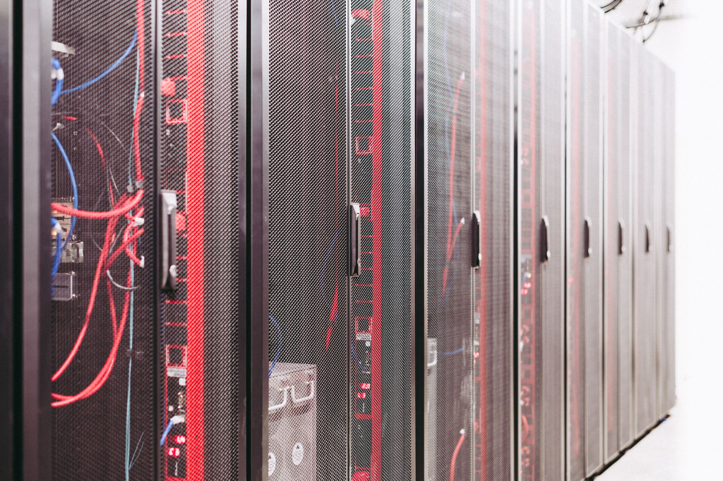 Rader av serverskåp med röda och blå nätverkskablar i en serverhall
