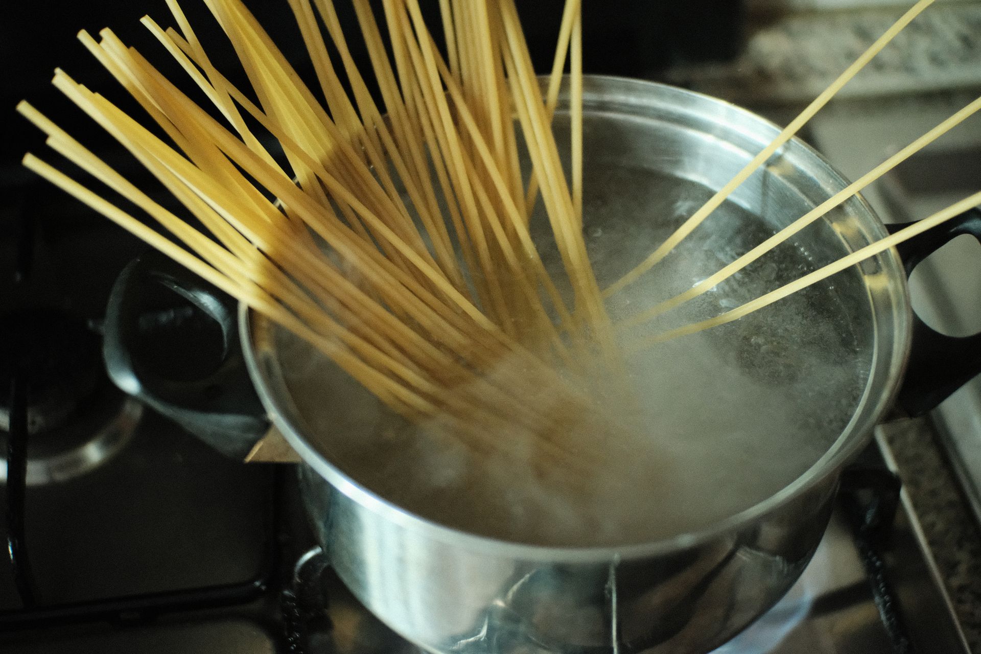 Torr spaghetti sänks ned i en stor kastrull med kokande vatten