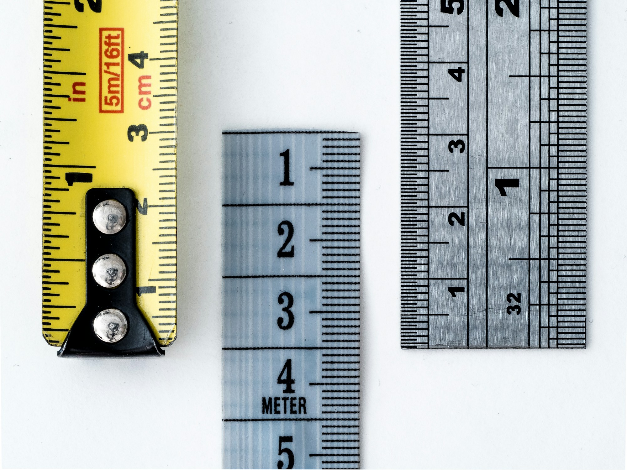 Måttband och två linjaler sida vid sida, med skalor i både tum och centimeter