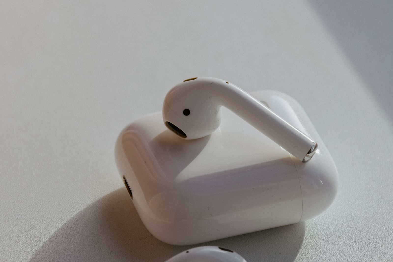 AirPods i sitt laddfodral på en ljus yta