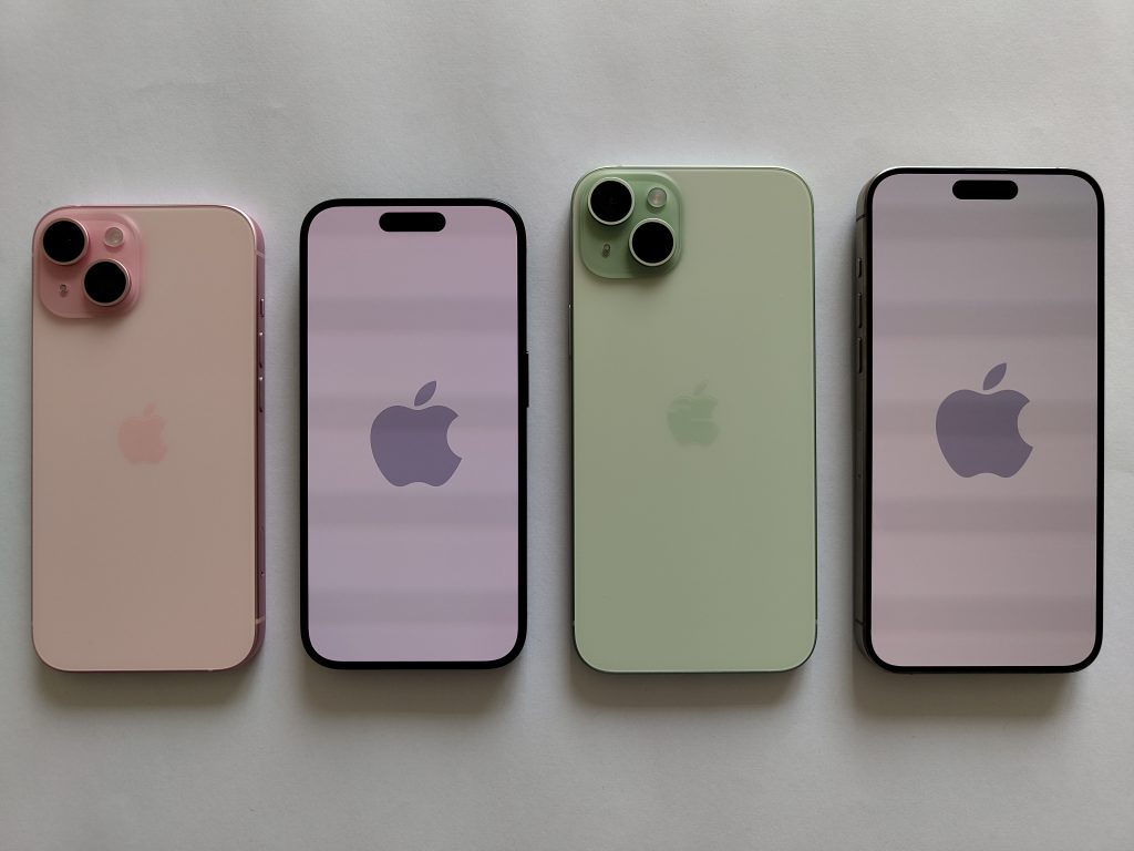 Fyra iPhone 15 i rosa och grönt, två med baksidan uppåt och två med skärmen uppåt, på vit bakgrund