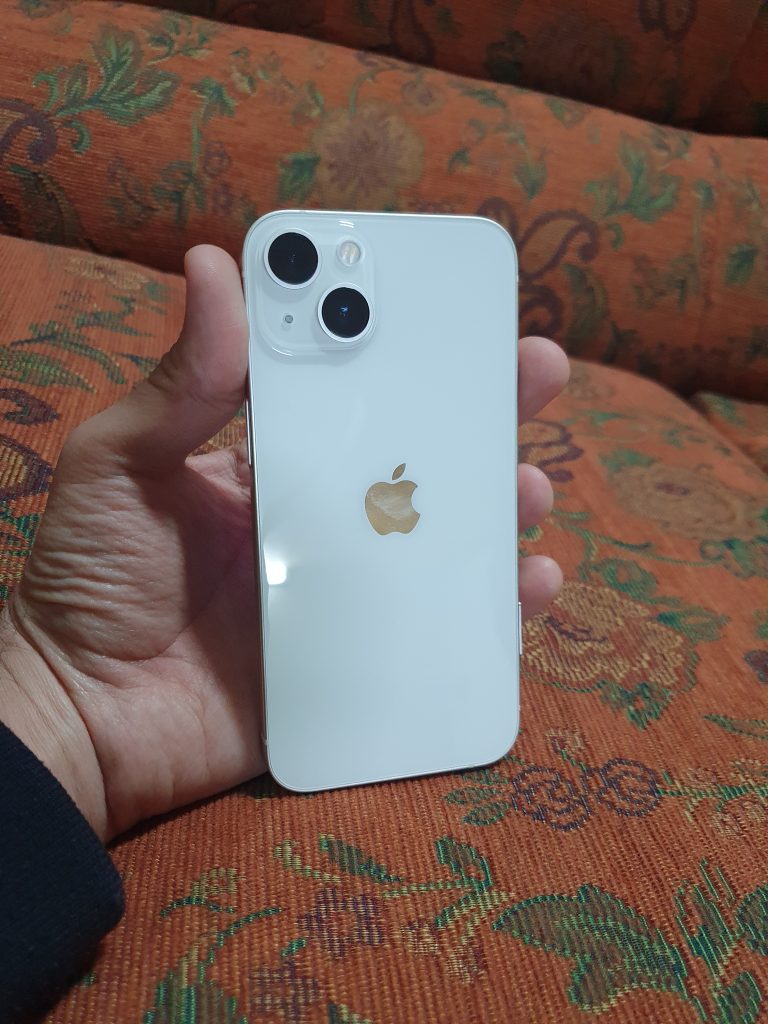 Vit iPhone 13 hålls upp i en hand