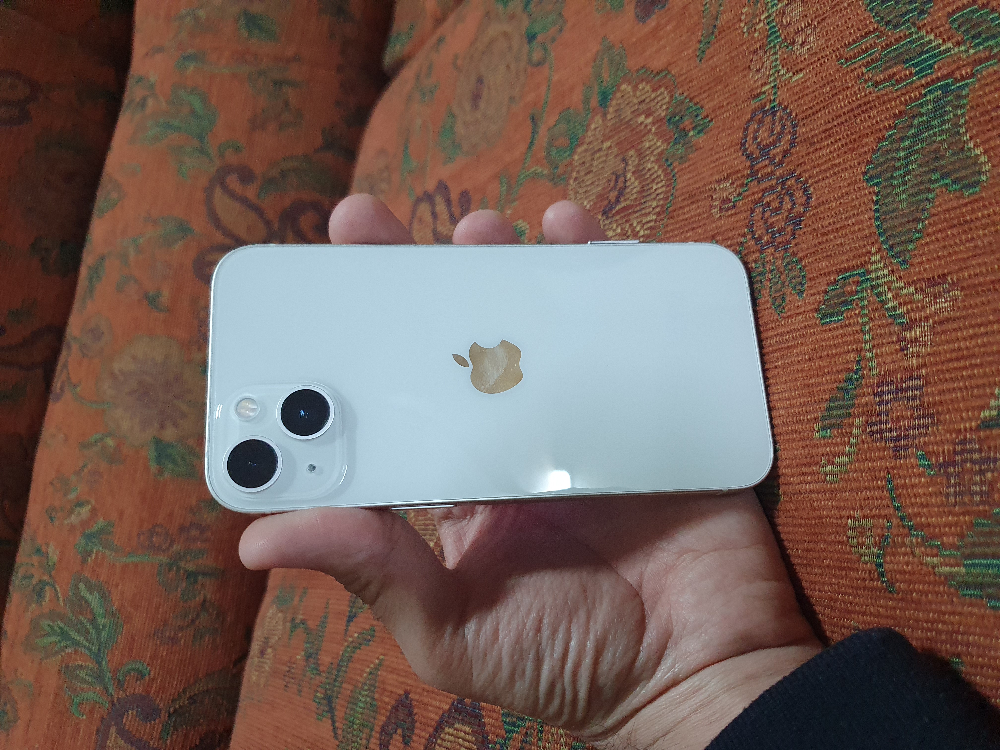 Vit iPhone 13 hålls upp i en hand