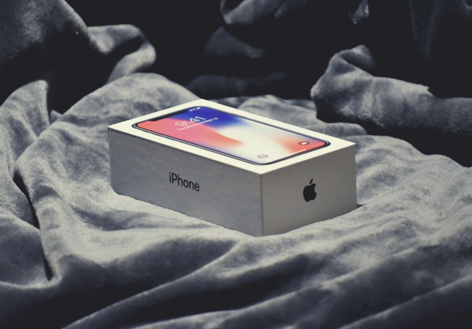 En iPhone-kartong ligger på ett grått tygunderlag