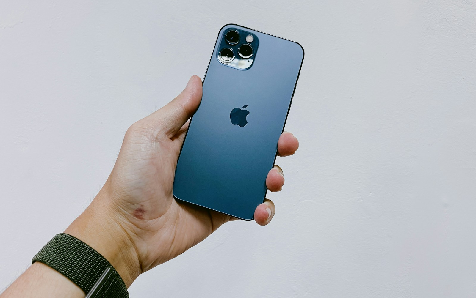 En iPhone 12 Pro i Pacific Blue som hålls upp i en hand