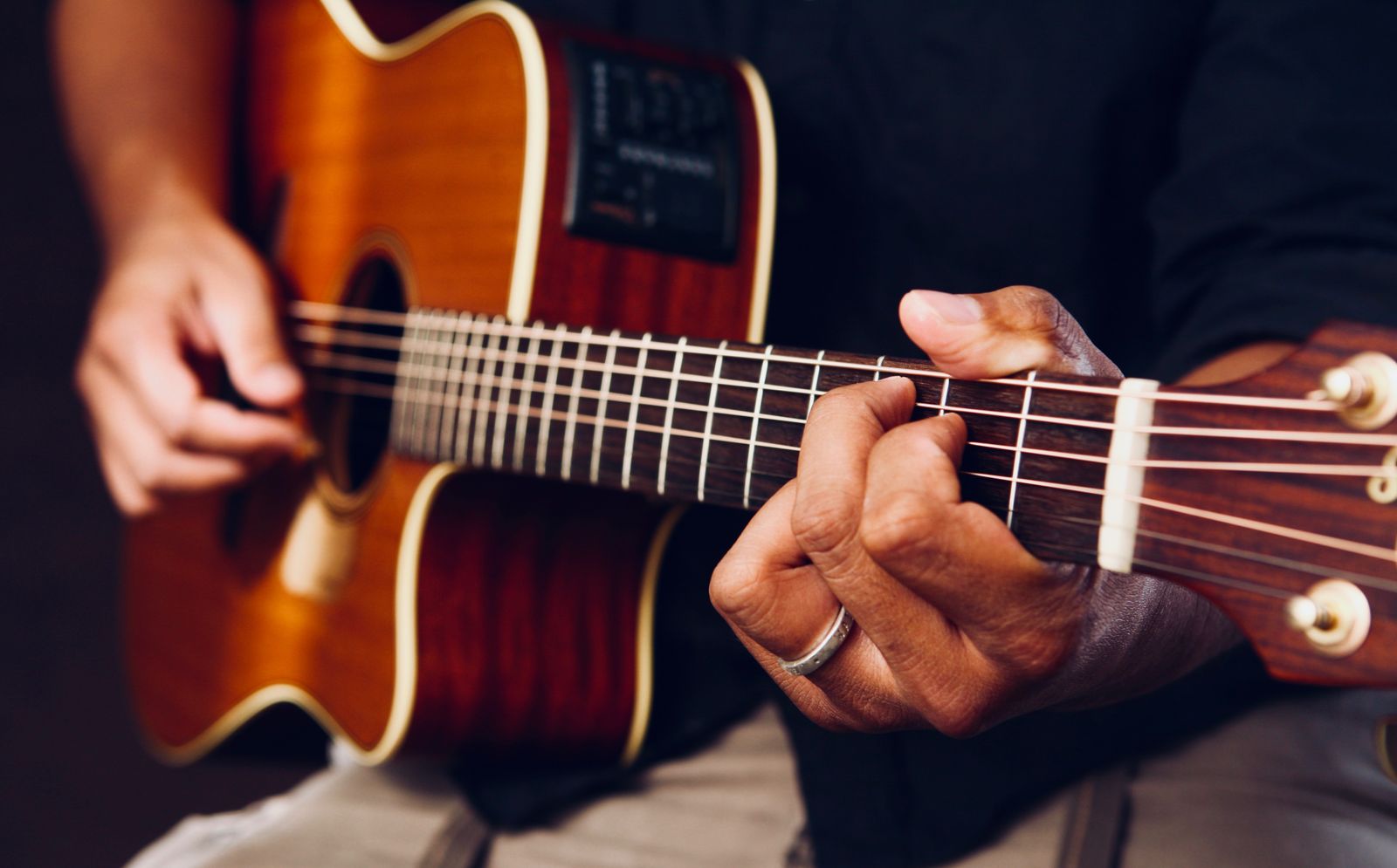 Händer som formar ett ackord på en akustisk gitarr