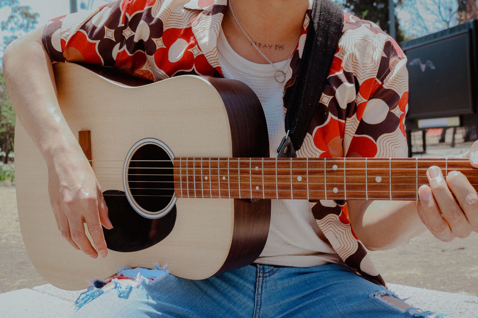 Person spelar akustisk gitarr utomhus