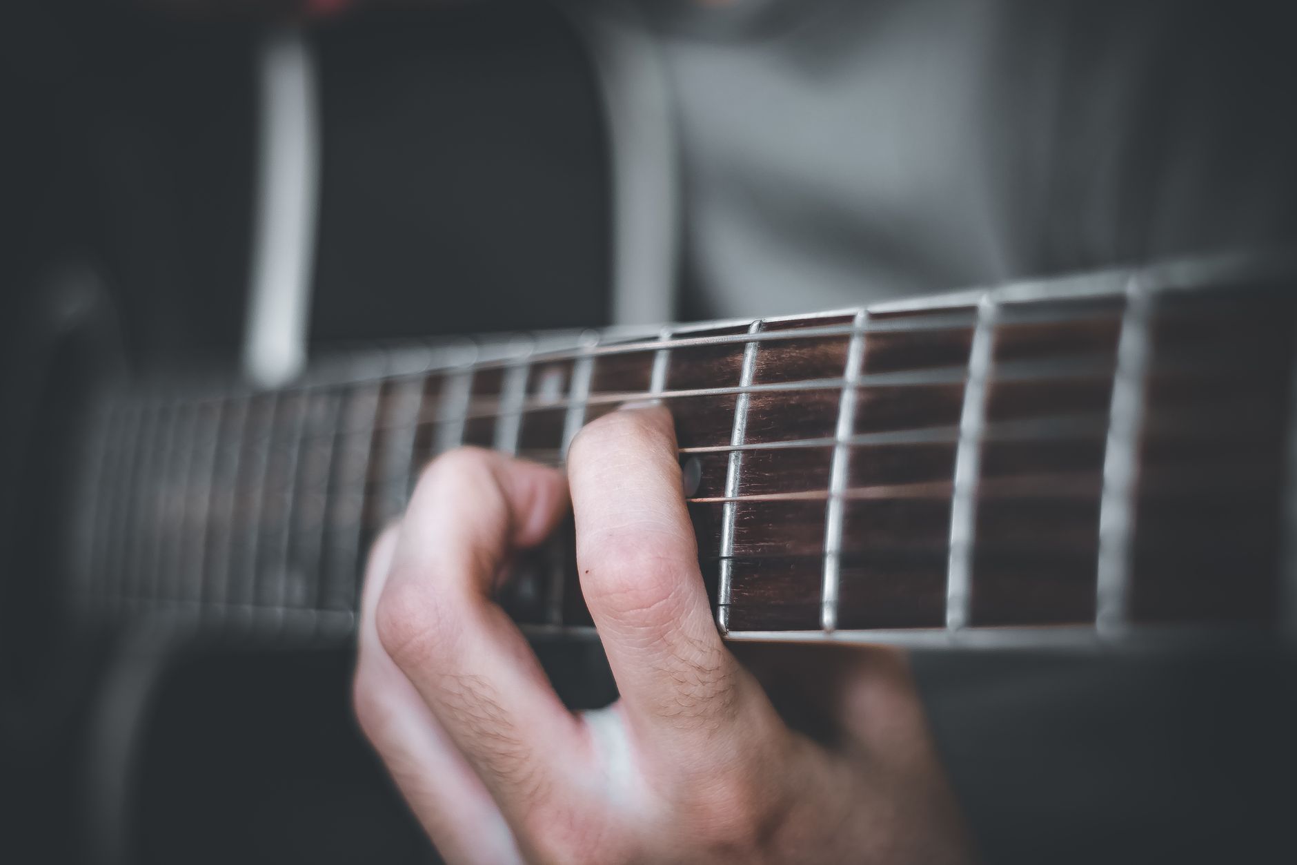 En hand som greppar ett ackord på en gitarrhals, närbild