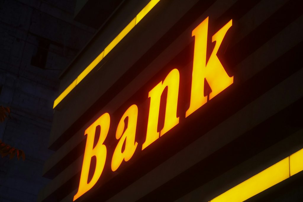 Upplyst skylt med ordet Bank på en byggnadsfasad
