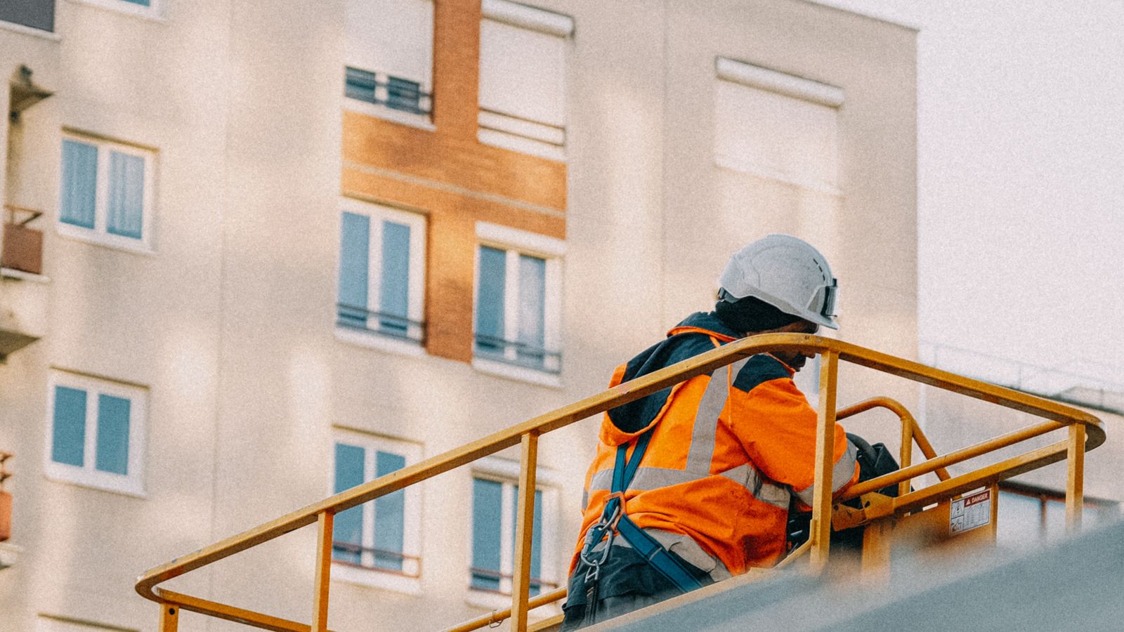 Fastighetsskötare inspekterar en byggnad från lift