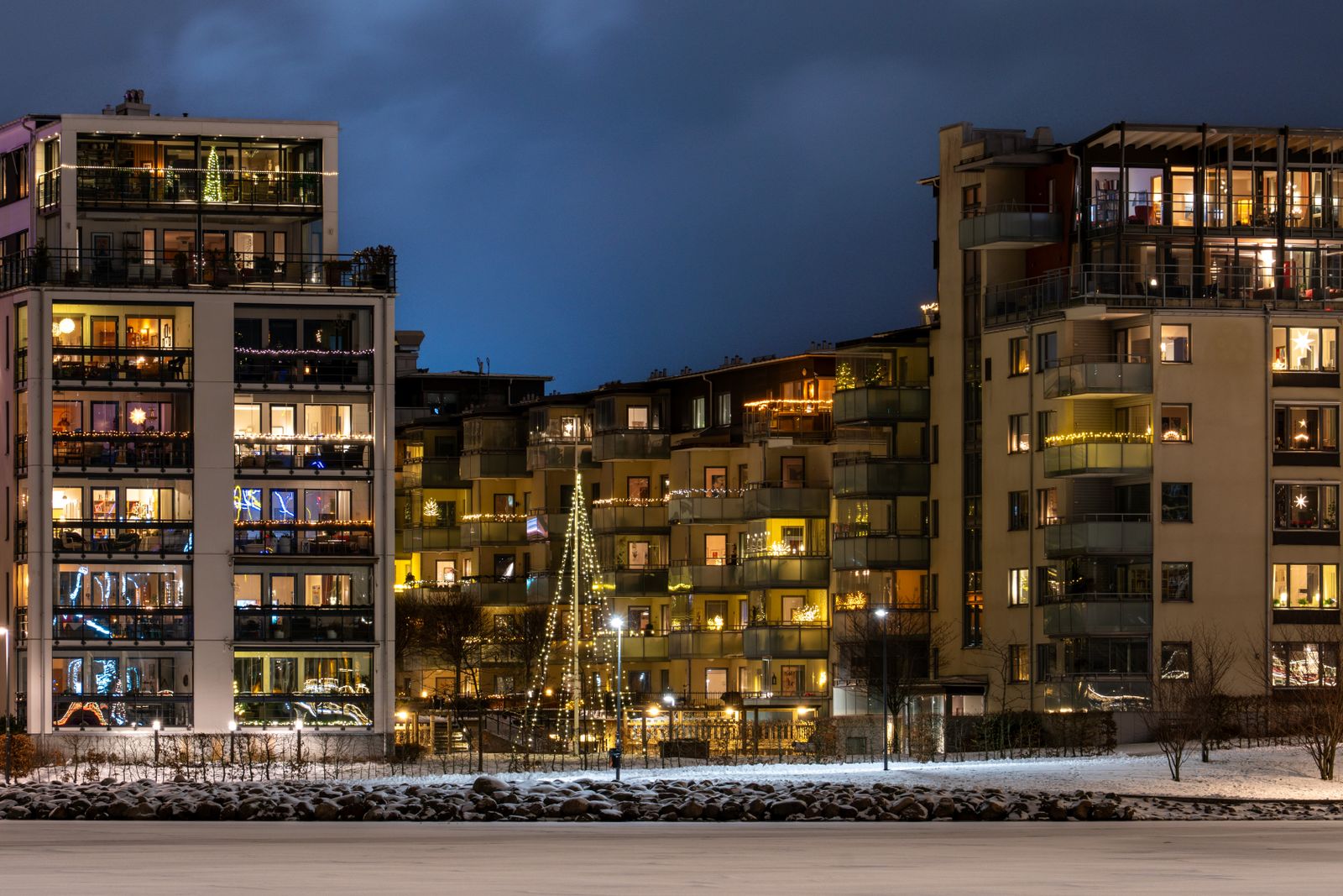 Modernt bostadsrättshus med upplysta fönster i vinterkväll