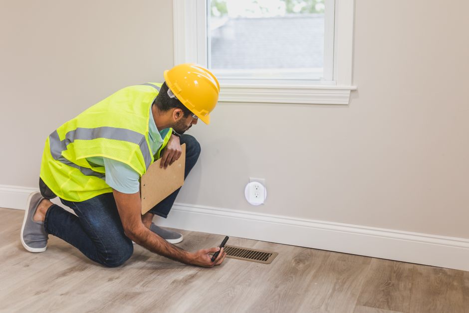 En besiktningsman kontrollerar ett ventilationsdon vid en OVK-besiktning