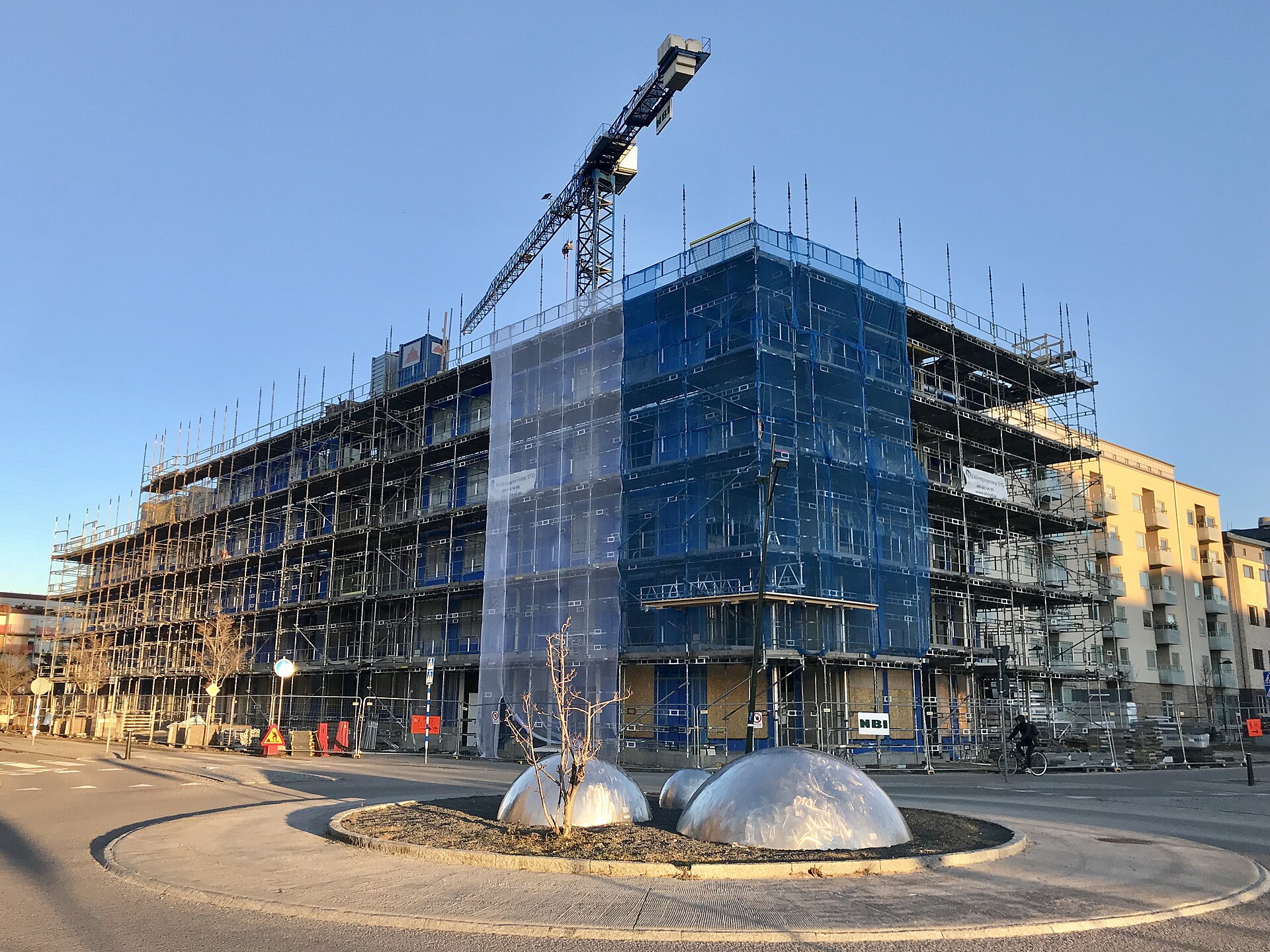 Flerbostadshus med blivande bostadsrätter under byggnad, inklätt i byggnadsställning med en tornkran ovanför