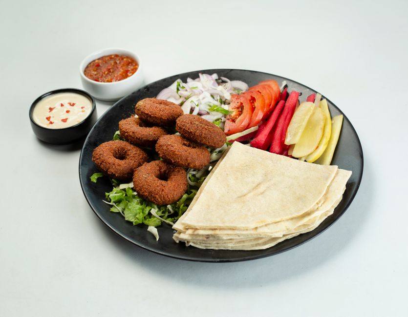 Tallrik med falafel, grönsaker, pitabröd och dippsåser